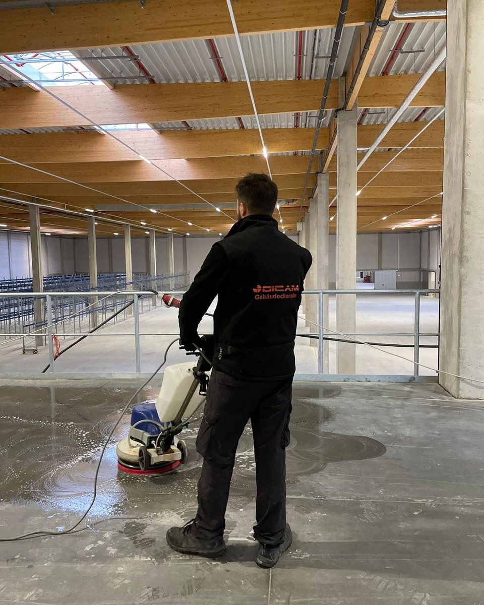 DICAM-Mitarbeiter reinigt mit einer Einscheibenmaschine den Boden einer Gewerbehalle