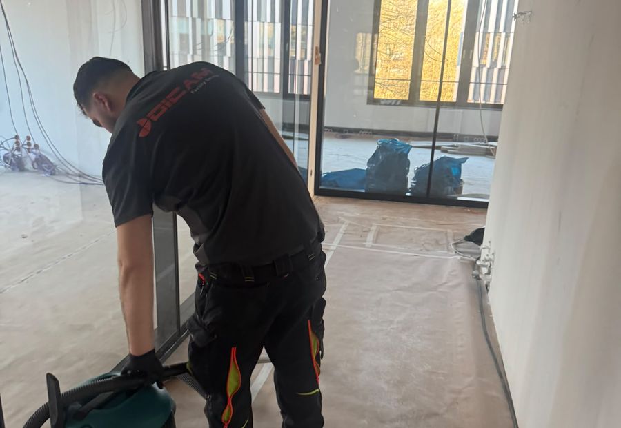 DICAM-Mitarbeiter saugt mit dem Industriesauger den Boden eines Rohbaus