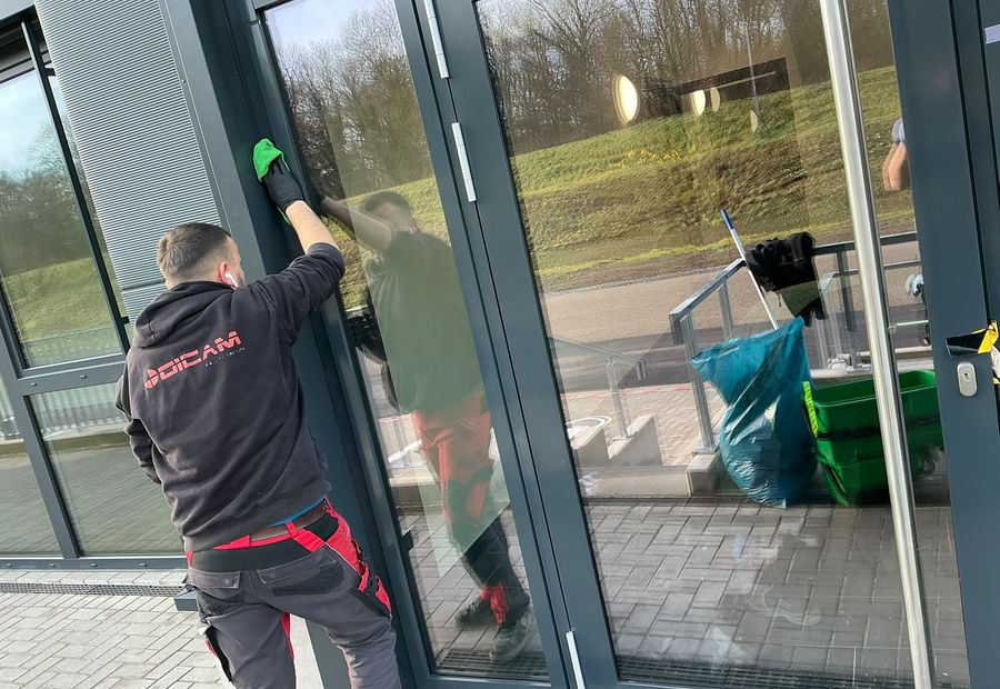 DICAM-Mitarbeiter reinigt eine Glasfassade mit dem Abzieher