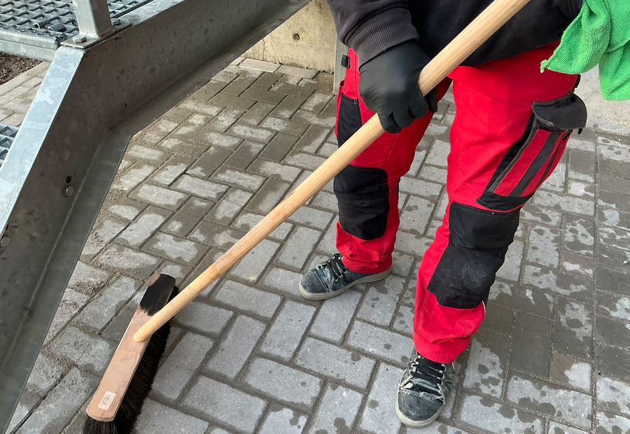 DICAM-Mitarbeiter kehrt eine gepflasterte Außenfläche